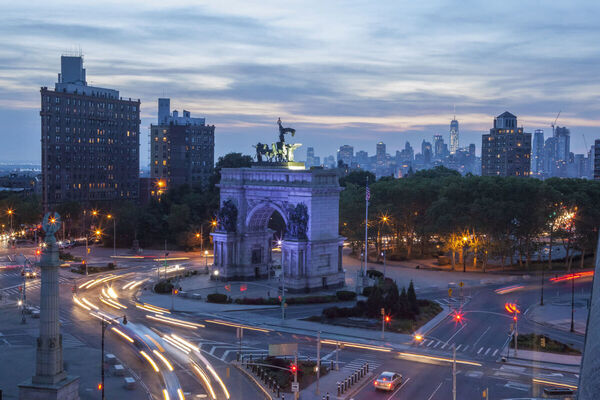 Grand Army Plaza at dusk — long-exposure showing traffic swirling around the arch